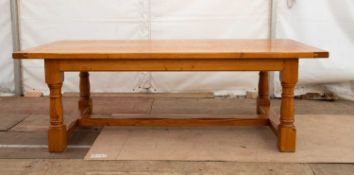 A modern light oak kitchen table with a rectangular top, a single frieze drawer and turned supports,