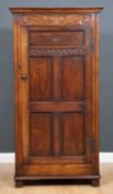 An oak hall cupboard in the 17th century style with single carved panel door and panelled sides,