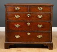 A Georgian oak chest of two short and three long drawers with later brass handles and raised on