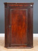 A George III mahogany hanging corner cupboard with fluted ornament either side of door, 78.5cm