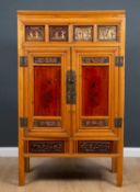 An Oriental cabinet inset with carved panels above the doors with painted decoration, the interior
