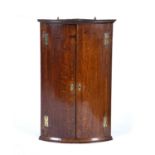 Oak bow front corner cupboard circa 1800, with brass hinges and escutcheons, 94cm high x 60cm