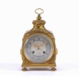 A 19th century French gilt brass travelling clock, the shaped top with hinged loop handle, the