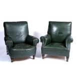 A matched pair of early 20th century library armchairs upholstered in green leather, one with rolled