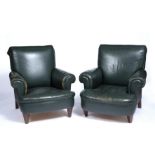 A matched pair of early 20th century library armchairs upholstered in green leather with rolled