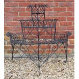 A black metal painted three tier plant display stand with basket fretwork designs and scrolling