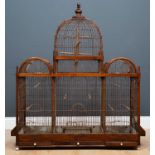 An old hardwood and wire framed bird cage, with central dome, three trays, feeders to either side