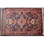 A mid to late 20th century Eastern red and blue ground woollen rug with geometric decoration,