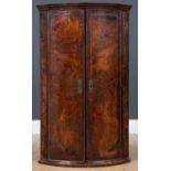An early 18th century bow fronted figured walnut veneered two door corner cupboard c.1700, with