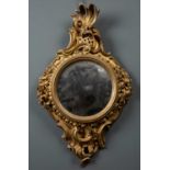 A small giltwood convex circular wall mirror, the frame with scalloped rim flanked by floral