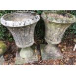 A pair of cast reconstituted stone garden planters of tulip form on circular bases, each 42cm