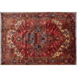 A Middle Eastern Heriz red ground rug with central cross motif and geometric decoration, 340cm x