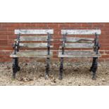 A pair of cast iron framed garden chairs, the white painted slat backs and seats with arms and