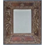 A repousse bronze wall mirror with beaded edge and figures of the Graces to either side of the bevel