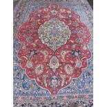 A late 20th century Middle Eastern red and blue ground carpet with stylised foliate decoration,