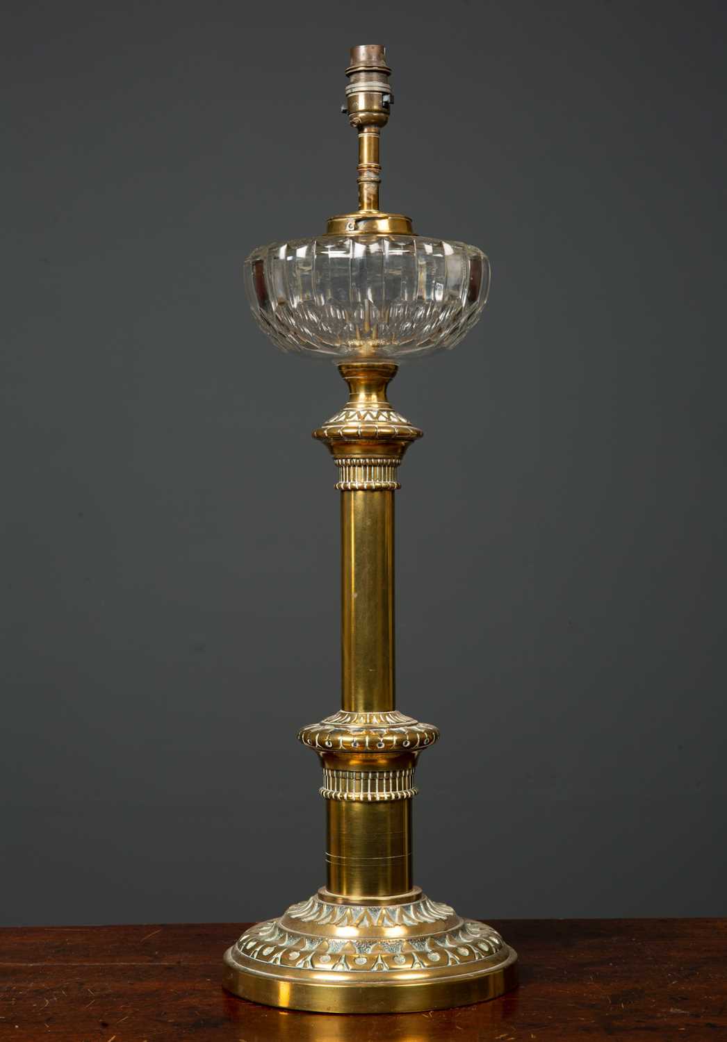 A Victorian brass based oil lamp with cut glass reservoir, later converted for use as an electric