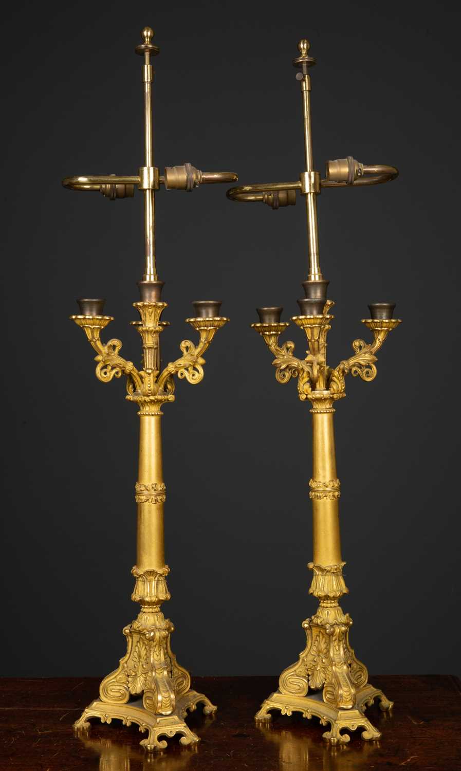 A pair of table lamps constructed from ormolu candlesticks with three scrolling branches and cast