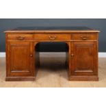 An early 20th century walnut partners desk with black leather inset top, panelled sides and with