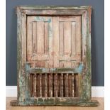 An antique Rajastani painted hardwood window frame with panelled shutters and turned supports to the