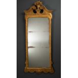 A giltwood carved wall mirror, with broken scroll pediment and urn crest, the edges engraved with