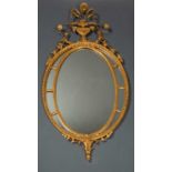 An Adam's style gilded gesso oval wall mirror, with carved beaded edge and foliate spray filled