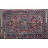 An Eastern blue and red ground rug with stylised foliate decoration and central flower head motif,