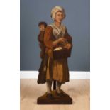 An antique dummy board in the form of a street vendor with child to her back, 38cm wide x 110cm