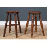 An antique turned elm stool with dished top, 30cm diameter x 54cm high together with a further