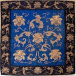 An Oriental silk blue ground panel decorated with stylised flowers in gold threads, set within a