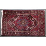 A Middle Eastern red ground rug with extensive geometric decoration and central diamond motif, 178cm