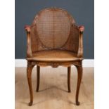 A French style beechwood framed chair with caned back, arms and seat, carved ornament and double