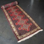 A late 20th century Middle Eastern style red ground runner with a banded border and stylised