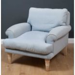 A deep light blue upholstered armchair originally acquired from Loaf, with turned tapering limed oak