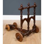 An Indian rosewood Rajastani baby walker with turned ornament, hardwood wheels and signature to