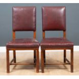 A pair of red leather dining chairs, the upholstered seat and seat back on octagonal wooden supports