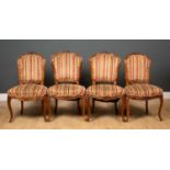 Two pairs of French walnut side chairs with carved frames and striped upholstery on carved sabre