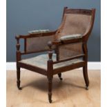 A bergere armchair with caned back and arm rests, with blue upholstered seat on wheeled column