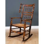 A Lancashire elm spindle back rocking chair with wool winder ornaments to the back, open arms,