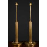 A pair of circular brass table lamps with fluted columns and circular bases, 59cm high to the