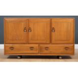 A 1970's Ercol light elm three-door sideboard, the pair of cupboard doors and single cupboard