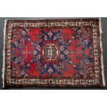 A Middle Eastern red ground rug with a banded border, stylised foliate decoration, 152cm x