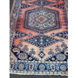 An Afghan red and blue ground rug with geometric decoration and a banded border, 320cm x