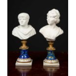 A pair of small marble busts, formed as a romanesque gentleman and lady with elaborate hairstyle, on