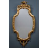 A 19th century gilt framed French wall mirror with shaped mirror plate beneath a shell and flower