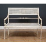 A white painted wooden and cane two seater bench, the wooden frame with caned inserts to the seat