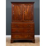 A George III mahogany press cupboard with secretaire drawer, the upper section with decorative