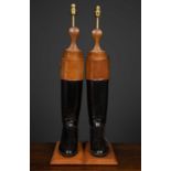 A pair of table lamps constructed from brown and black leather riding boots, mounted on