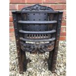 A small Victorian cast iron fire grate insert for a bedroom, with decorative ornament to the