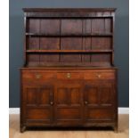 An early 19th century oak dresser with plate rack above, three doors and two panelled cupboard