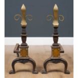 A pair of Victorian brass and cast iron fire dogs, with embossed fleur-de-lis form finials on curved